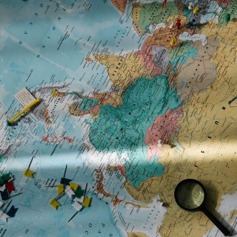 Exploration tools, including a compass and magnifying glass, placed on a colorful world map.